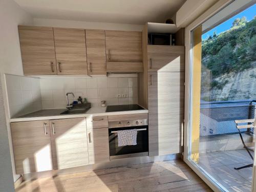 une cuisine avec des placards en bois et une grande fenêtre dans l'établissement Magnificent renovated apartment, 2 rooms of 45 m2, close tothe sea, top floor, terrace, à Nice