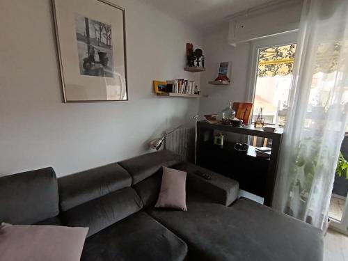 - un salon avec un canapé noir et une fenêtre dans l'établissement Appartement équipé, Roquebrune Menton plage mer ., à Roquebrune-Cap-Martin