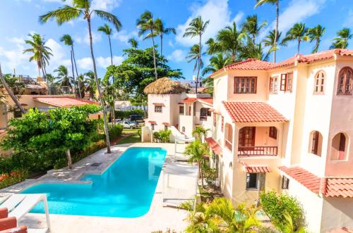 蓬塔卡納的住宿－CARAIBICO DELUXE Beach Club & SPA，享有带游泳池和棕榈树的别墅的空中景致