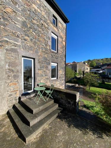 a stone house with a table and a bench on the stairs at L'Oustal Des Dômes in Orcines