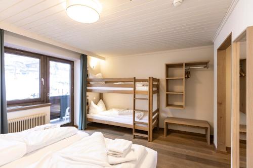 a room with two bunk beds and a window at Hotel Pinzgauerhof - Inclusive Evening Dinner in Saalbach Hinterglemm