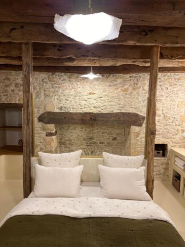 Ce lit se trouve dans une chambre dotée d'un mur en briques. dans l'établissement Maison Lou Piade, à Sarlat-la-Canéda