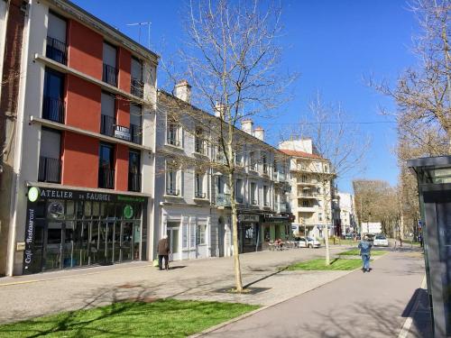 une rue avec des bâtiments et des gens qui marchent sur le trottoir dans l'établissement Résidence Noisica, à Saint-Étienne