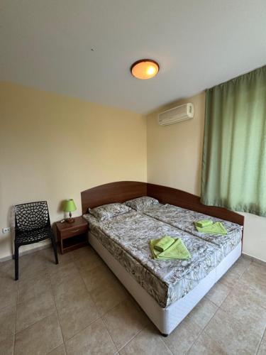 a bedroom with a bed and a chair and a window at Семеен хотел САМИ in Kranevo