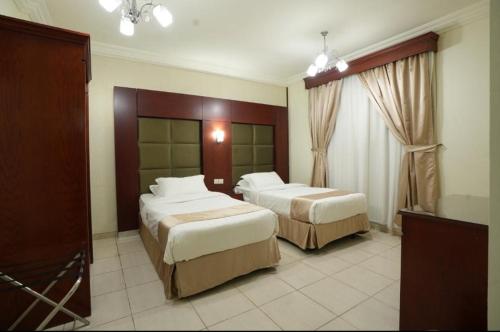 ein Hotelzimmer mit zwei Betten und einem Fenster in der Unterkunft سيزن للوحدات السكنية in Dschidda