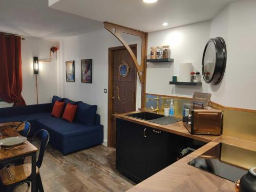Una sala de estar con un sofá azul y una cocina. en DiscoveryHome 4Pers Disneyland Paris à 10 min bus, Free Parking, Outlet Shopping, Village Nature, en Magny-le-Hongre