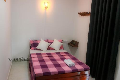 ネゴンボにあるJaya Villaのピンクと紫のチェッカーベッド付きのベッドルーム1室