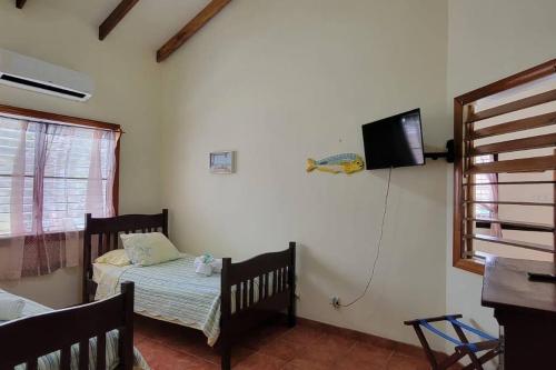 ein Schlafzimmer mit einem Bett und einem Fernseher an der Wand in der Unterkunft Villa Hermosa- 2 Bedroom Home in Caye Caulker