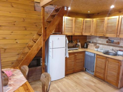 a kitchen with a white refrigerator and wooden cabinets at POD SOSNAMI Ośrodek Wypoczynkowy Boszkowo Letnisko in Boszkowo