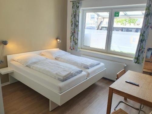 Bett in einem Zimmer mit einem Fenster und einem Tisch in der Unterkunft Aparthotel Sanni in Bremen