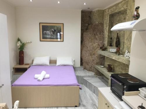 a bedroom with a bed with purple sheets and a microwave at Agnes Rooms in Pelekas