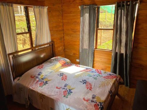 a bed in a room with two windows at Cabaña Princesa Roja - PERFECT view of the valley! in San Pablo