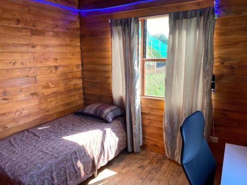 Dormitorio con cama y ventana en una cabaña de madera en Cabaña Princesa Roja - PERFECT view of the valley!, en San Pablo