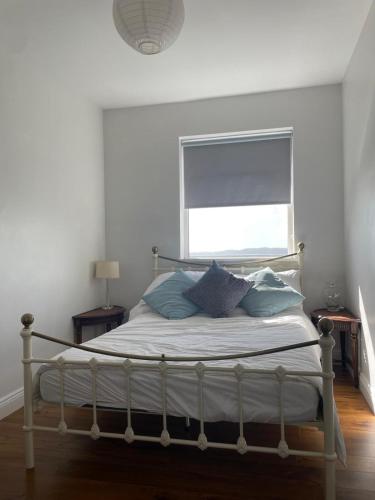 a bed with blue pillows in a bedroom with a window at Grianan, Cobh in Cobh