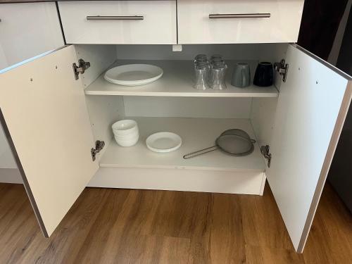 a white cabinet with plates and dishes in it at Appartement avec garage in La Ferté-Gaucher