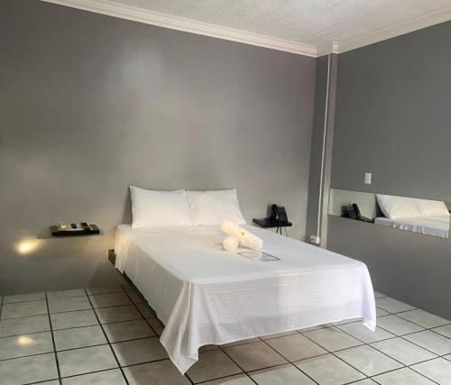 a bedroom with a white bed with two teddy bears on it at San Isidro, Perez Zeledon - Hotel Dubai in San Isidro