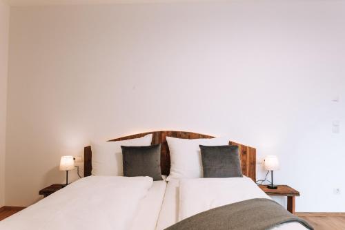 um quarto com uma cama com lençóis brancos e almofadas em Matscherhof Lana em Lana
