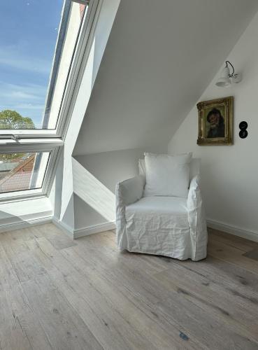 a white chair in a room with large windows at Strandhaus WOTAN in Kühlungsborn