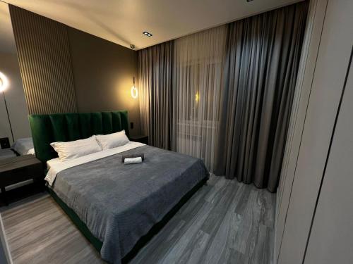 Schlafzimmer mit einem Bett mit einem grünen Kopfteil in der Unterkunft Lux в ЖК K7-Family рядом аэропорт in Atyrau