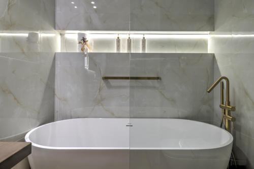 a white bath tub in a bathroom with marble walls at Marie Suite in Nafplio