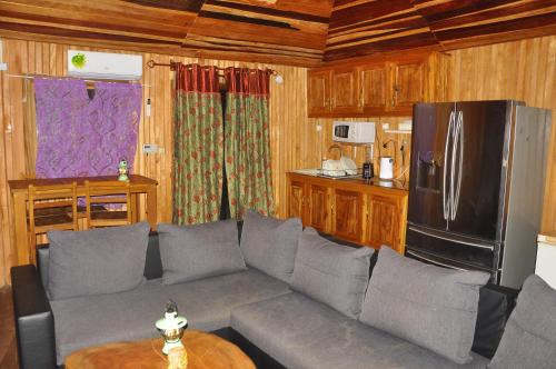 a living room with a gray couch and a refrigerator at Appartement Chalet type f3 in Kribi