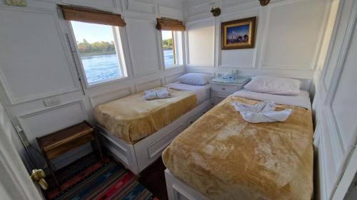 Habitación pequeña con 2 camas y ventana en Dahabiya Nile Cruise, en Luxor