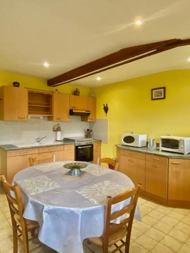 une cuisine avec une table avec des chaises et un micro-ondes dans l'établissement L'oscar, à Saint-James