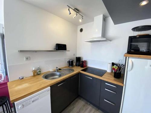 une petite cuisine avec un évier et un micro-ondes dans l'établissement Résidence Le Casino - Appartement devant la plage vue mer parking privé MAE-6404, à Perros-Guirec