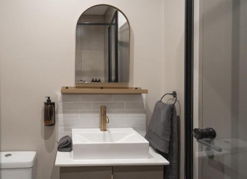 ein Badezimmer mit einem weißen Waschbecken und einem Spiegel in der Unterkunft Top-Floor Urban Oasis located in the heart of Sandton City Center in Johannesburg
