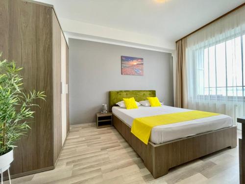 1 dormitorio con 1 cama con almohadas amarillas en Vedere la mare apartament en Mamaia
