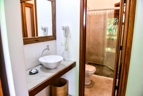 een badkamer met een wastafel, een toilet en een spiegel bij Suítes Forte Rocha in Ilhabela