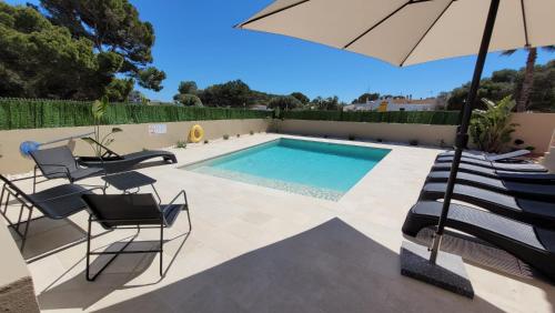 una piscina con sillas y sombrilla en Villa Victoria Paradise, en Cala en Blanes