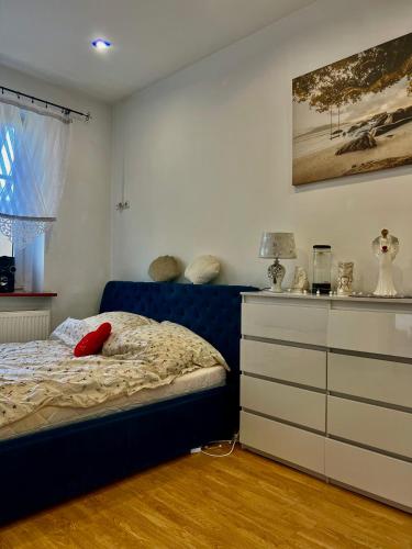 a bedroom with a blue bed and a dresser at Apartament Muszelka in Bytom