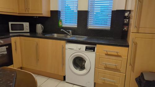 eine Küche mit einer Waschmaschine und einem Waschbecken in der Unterkunft Alexander Apartments Heaton in Heaton