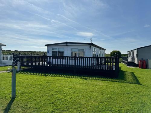 a white house with a fence in the grass at Sunshine Lodge Haven Lakeland in Flookburgh
