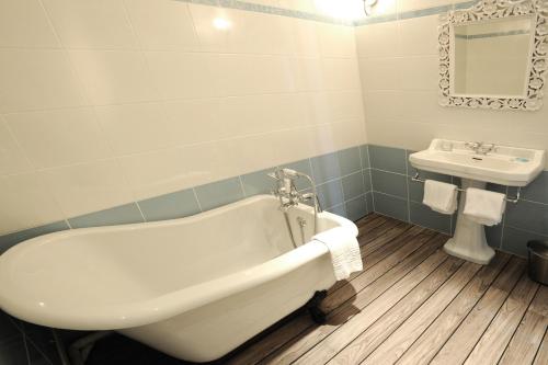 a bath tub sitting next to a toilet in a bathroom at La Ferme des Mares, The Originals Relais (Relais du Silence) in Saint-Germain-sur-Ay