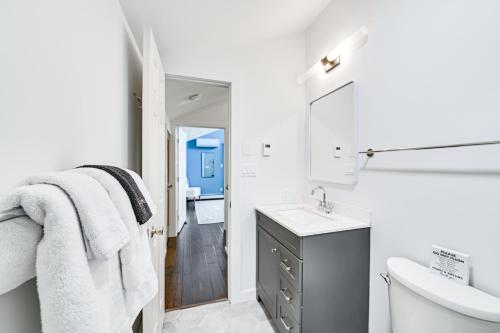 a white bathroom with a sink and a toilet at The Mountain House Windham Retreat with Hot Tub! in Windham