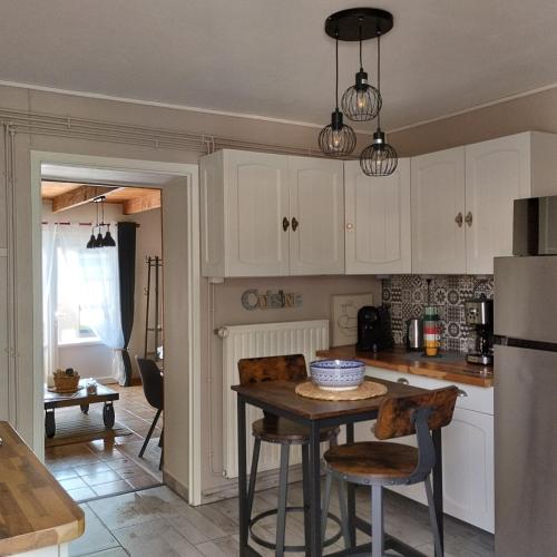 une cuisine avec des armoires blanches et une table avec des chaises dans l'établissement Maison de village en Périgord, à Singleyrac