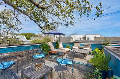a patio with chairs and tables and an umbrella at Elegant Sunlit Home with Private Rooftop Oasis in Charleston