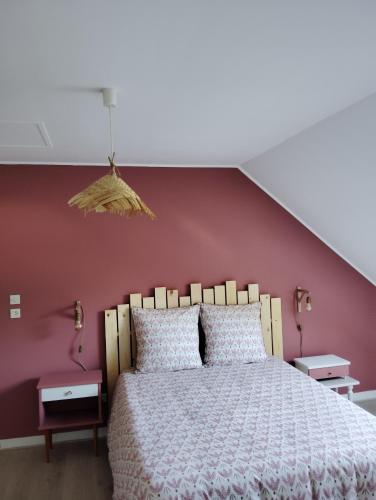 une chambre avec un grand lit avec un mur rouge dans l'établissement Maison de famille, à Écommoy