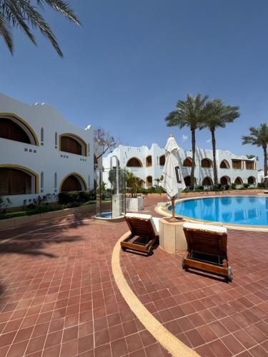 a resort with two lounge chairs and a swimming pool at Sharm Prestige Room 52 - Luxury sea view at coral bay in Sharm El Sheikh