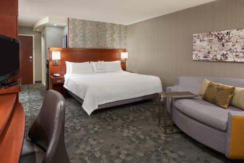 a hotel room with a bed and a couch at Courtyard by Marriott Kingston Highway 401 in Kingston