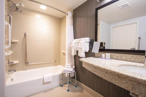 a bathroom with a bath tub and a sink and a bath tub at Courtyard by Marriott Kingston Highway 401 in Kingston