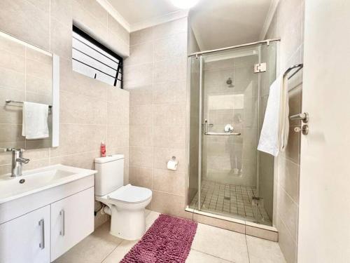 uma casa de banho com um chuveiro, um WC e um lavatório. em Nala Realty at The Aura em Sandton