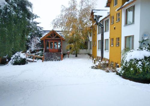 un patio cubierto de nieve con una casa con puerta en La Balconada by DOT Boutique en Villa Pehuenia