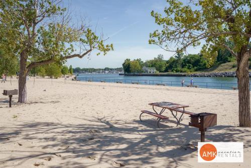 a picnic table on a sandy beach next to a lake at Downtown Holland Charmer in Holland