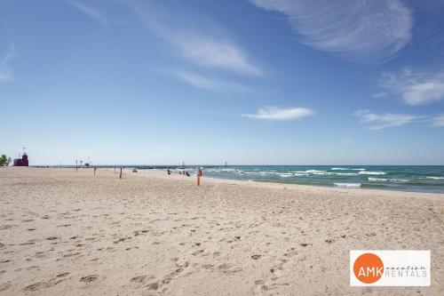a beach with people walking on the sand and the ocean at Downtown Holland Charmer in Holland