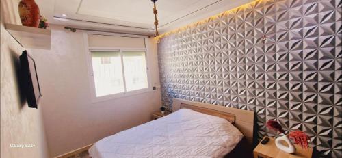 a small bedroom with a bed and a wall at El kawtar 18 appart-hôtel in Kenitra