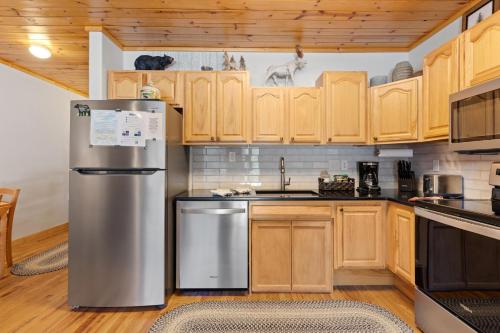 a kitchen with wooden cabinets and a stainless steel refrigerator at Bugle Pointe B04 by Estes Park Condos in Estes Park