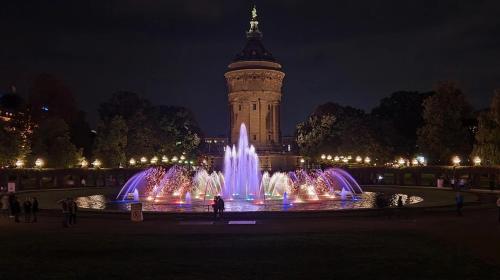 a fountain in front of a clock tower at night at Mannheim Comfort - 4 Star Apartments for you in Mannheim
